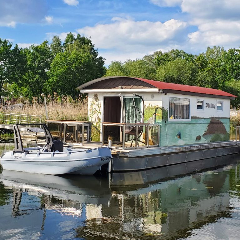 Bieberburg am Steg mit einem Beiboot vor einer malerischen Landschaft.